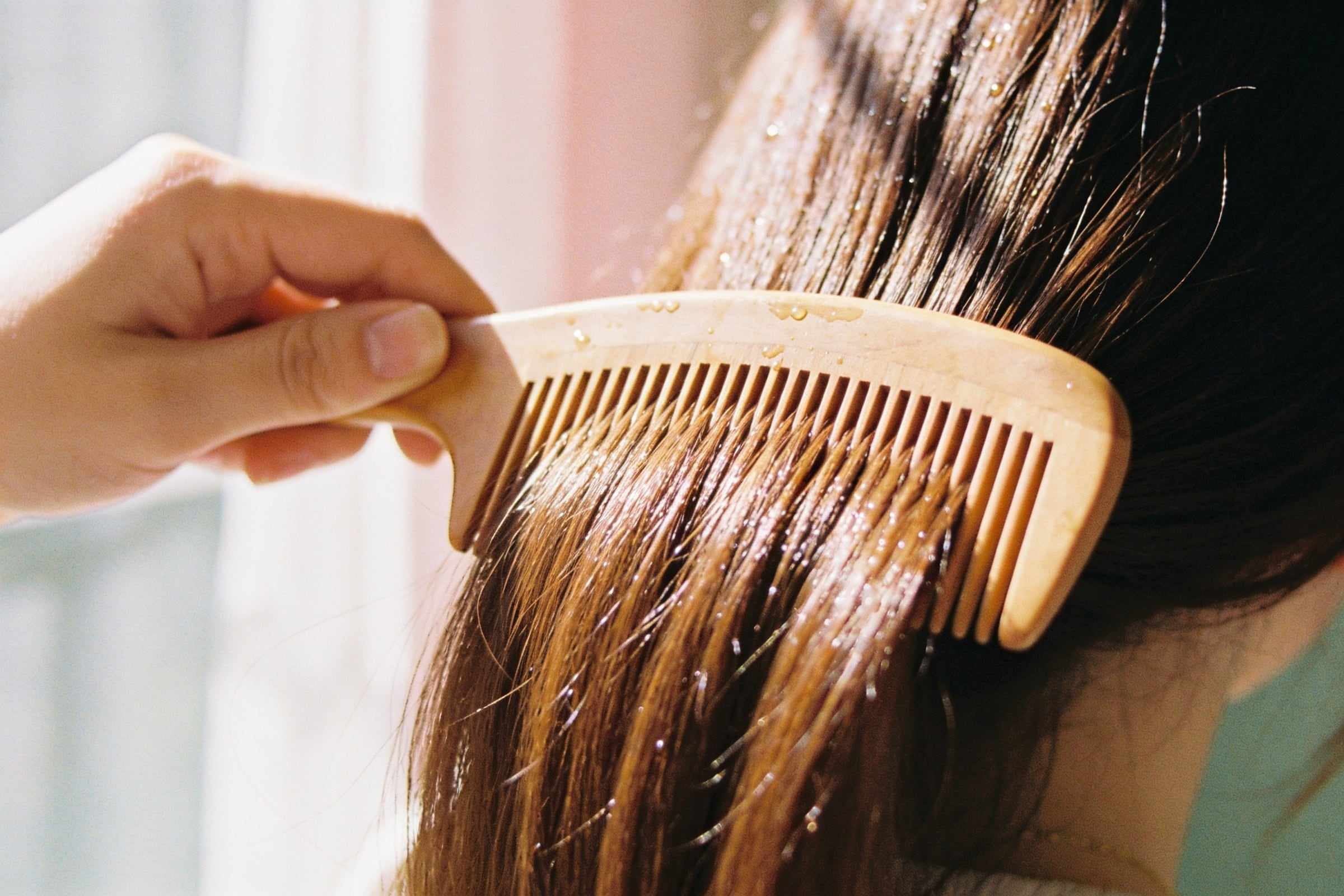 A wooden comb gliding through very glossy chestnut hair.