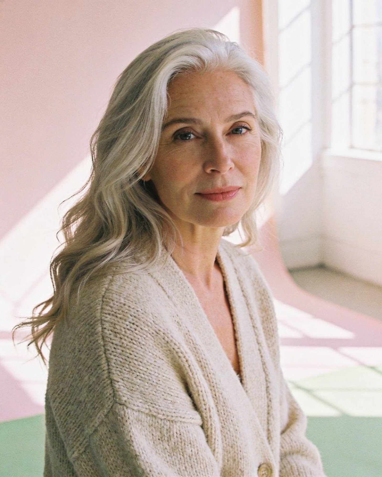 Rosa, with long silver-blonde waves and an oatmeal cardigan, in the sunny studio.